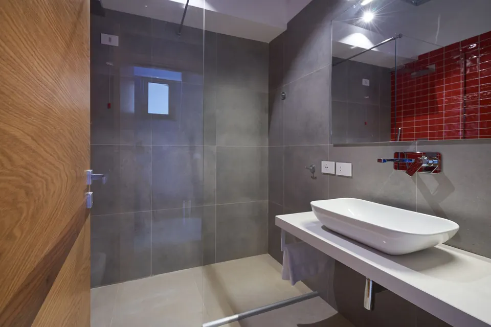 Bagno in pietra grigia con doccia a filo