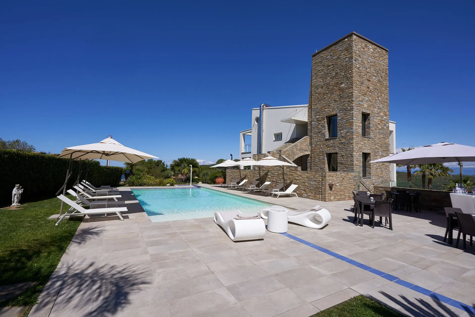 La piscina di Torre Difyos con la torre in pietra e gli ombrelloni